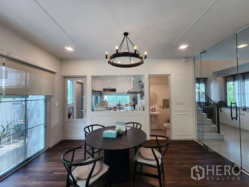 Detached House for rent or sale in Bang Phli, Samut Prakan - Dining room with round table, chandelier and pass-through window to the kitchen.
