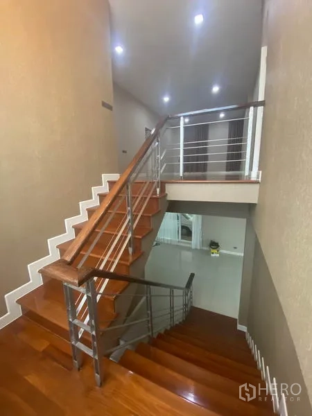 Detached House for rent in Prawet, Bangkok - Polished wooden staircase with stainless-steel handrails leading to the upper floor landing.
