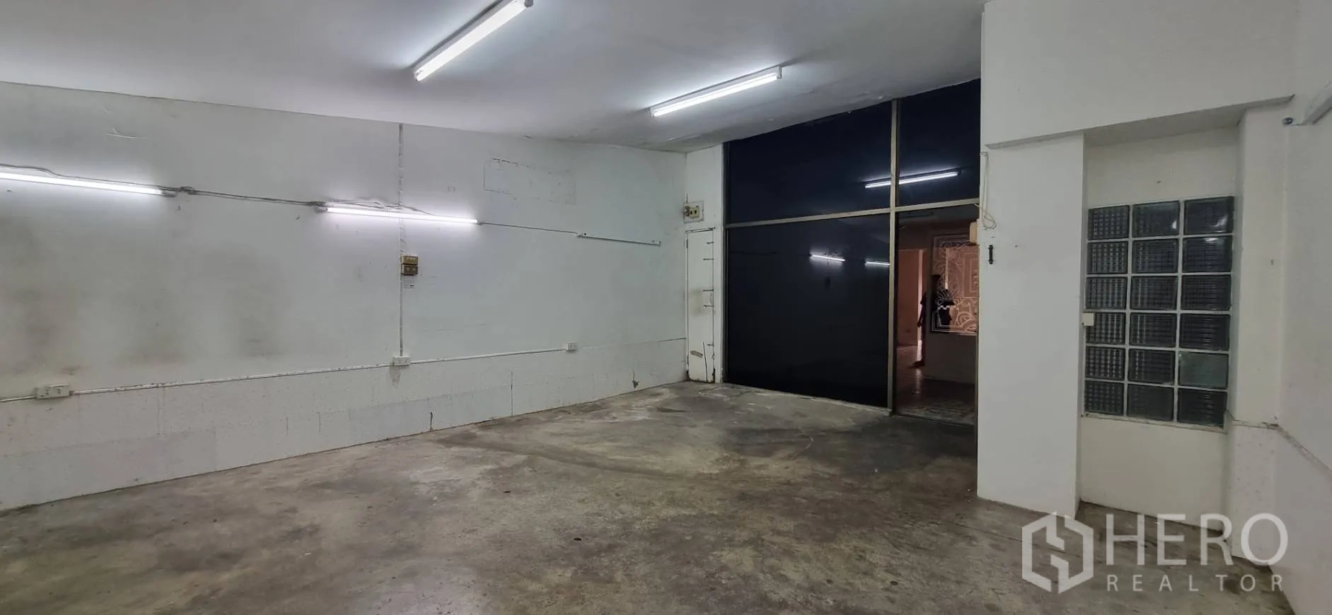 Shophouse for rent or sale in Bangkok - Storage room view toward a sliding dark glass partition and glass block wall.