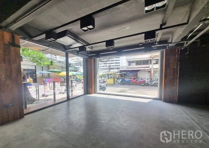 Retail Space for rent in Bang Rak, Bangkok - Open-plan retail interior with wide sliding glass doors to the street, concrete floor and exposed ceiling lighting.