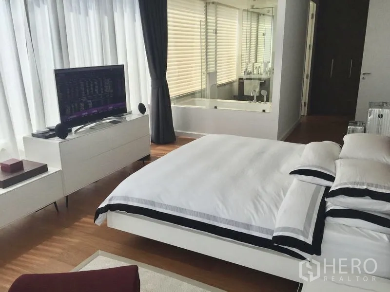 Condominium for rent or sale in Pathum Wan, Bangkok - Bright master bedroom with king bed, TV console and a glass-walled ensuite bathroom