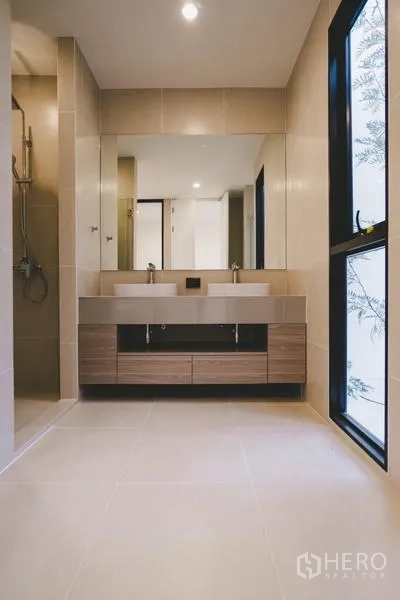 Townhouse for sale in Phra Khanong, Bangkok - Spa-style bathroom featuring a double vanity, large mirror and a glass-enclosed shower.