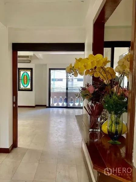 Home Office for rent in Khlong Toei, Bangkok - Hallway leading to balcony with balustrade, stained-glass window and display shelf.