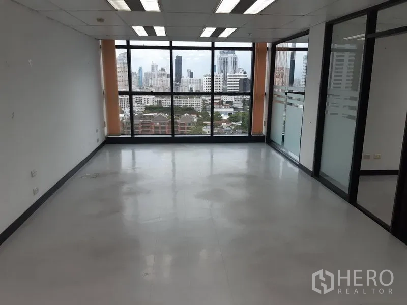 Office Space for rent in Watthana, Bangkok - Long rectangular office with large windows and overhead lighting facing the city.