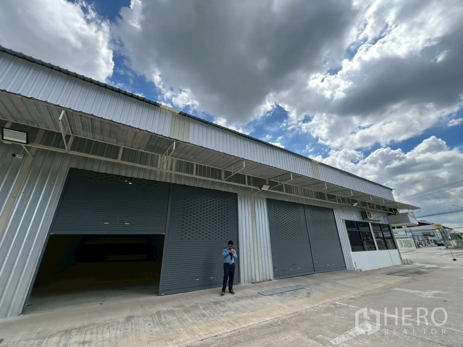Warehouse for rent in Min Buri, Bangkok - Front elevation of warehouse units with multiple roller shutters and a covered canopy.