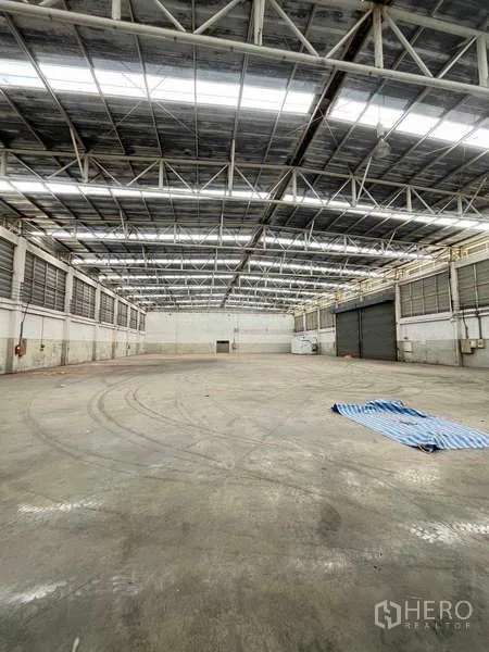 Warehouse for rent in Lat Krabang, Bangkok - High-ceiling warehouse interior with steel trusses and large roller shutter doors.