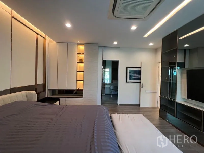 Detached House for sale - Primary suite showing built-in wardrobes, illuminated shelving and mirrored TV wall.