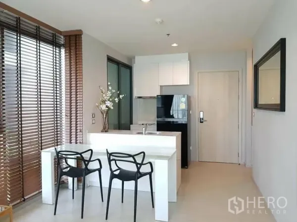 Condominium for rent or sale in Khlong Toei, Bangkok - Compact kitchen with white cabinetry, black fridge, glass dining table and entry door.
