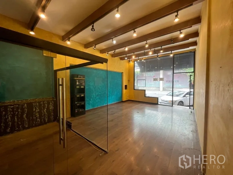 Retail Space for rent in Watthana, Bangkok - Open-plan shop interior with wood floors, exposed beams, track lighting, and floor-to-ceiling storefront window.