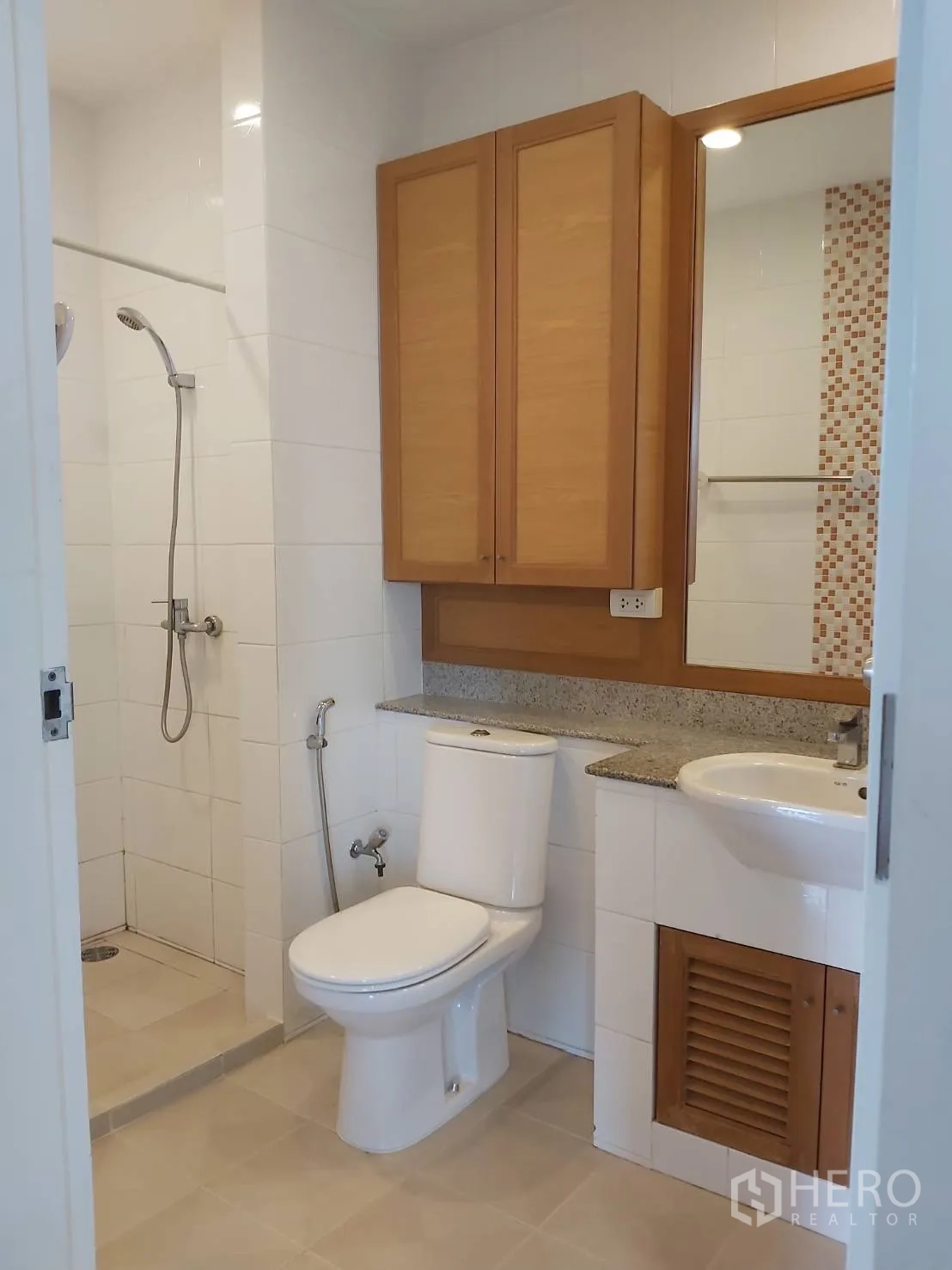 Apartment for rent in Khlong Toei, Bangkok - Second bathroom with walk-in shower, toilet, mirror cabinet, and granite countertop.
