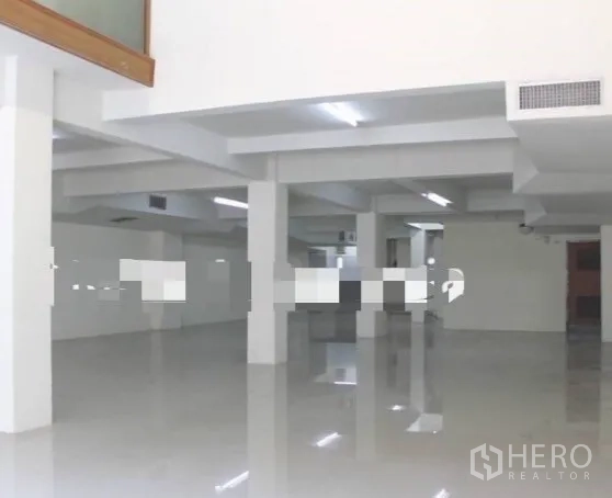 店屋 出租在Khlong Toei, Bangkok - 上层宽敞工作区，白色立柱、亮面地面与条形顶灯。