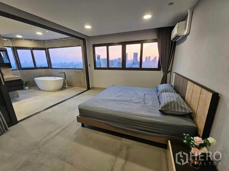 Condominium for rent or sale - Master bedroom with large windows and open ensuite featuring a soaking tub.