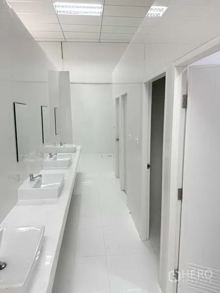 Factory for rent in Pathum Thani - Clean communal restroom corridor with multiple sinks and cubicles.