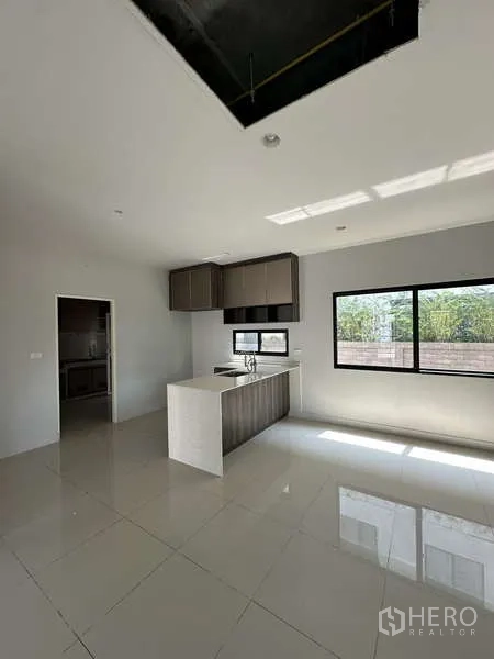 Detached House for sale in Lam Luk Ka, Pathum Thani - Sunlit kitchen with island bench and wide picture window.