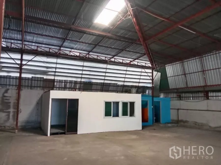 Warehouse for rent in Saphan Sung, Bangkok - Compact internal office and restroom block inside the warehouse beneath a corrugated roof.