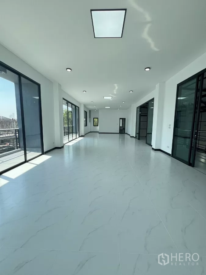 Warehouse for sale in Lam Luk Ka, Pathum Thani - Bright open-plan office floor with large glass windows, white tiled flooring and recessed LED lights.
