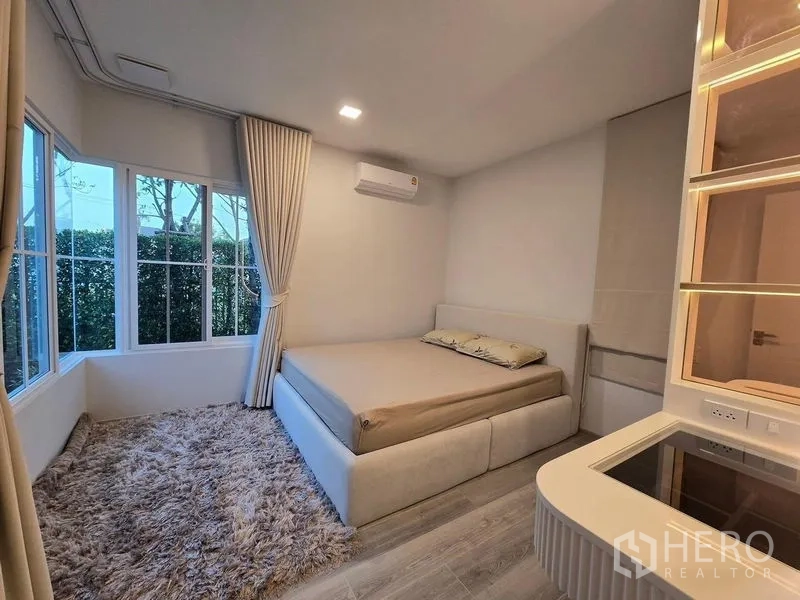 Detached House for rent in Bang Phli, Samut Prakan - Ground‑floor bedroom with panoramic corner windows, plush rug and built‑in shelving.