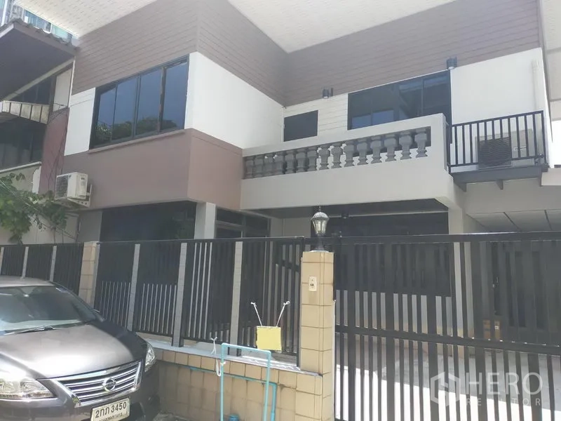 Detached House for rent in Watthana, Bangkok - Modern two-storey detached house facade with balcony, black gate and on-site parking.
