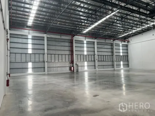 Factory for rent in Bang Pakong, Chachoengsao - Side view of warehouse showing ventilated cladding, red fire sprinkler pipes and tall walls.