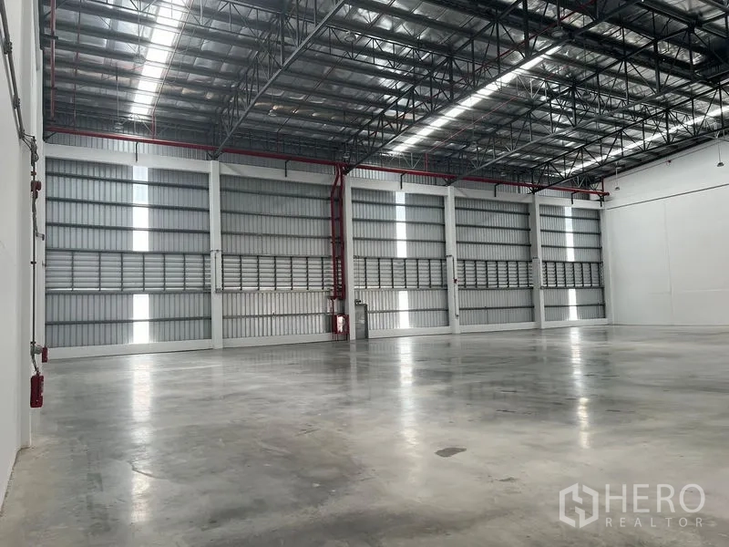 Factory for rent in Bang Pakong, Chachoengsao - Side view of warehouse showing ventilated cladding, red fire sprinkler pipes and tall walls.