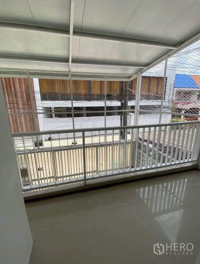 Townhouse for rent in Phra Khanong, Bangkok - Covered balcony with white railing and safety mesh facing the neighborhood lane.