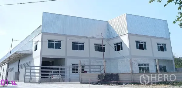 Warehouse for rent or sale in Lam Luk Ka, Pathum Thani - Front elevation of a large warehouse and office building with sliding gate.
