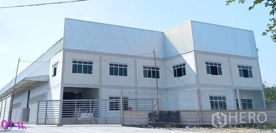 Warehouse for rent or sale in Lam Luk Ka, Pathum Thani - Front elevation of a large warehouse and office building with sliding gate.