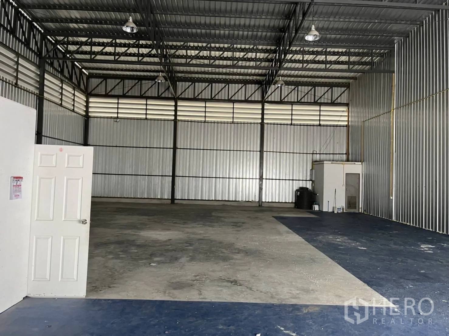 Warehouse for rent in Bang Phli, Samut Prakan - Open-plan warehouse interior with high steel trusses, concrete floor, and small internal office.