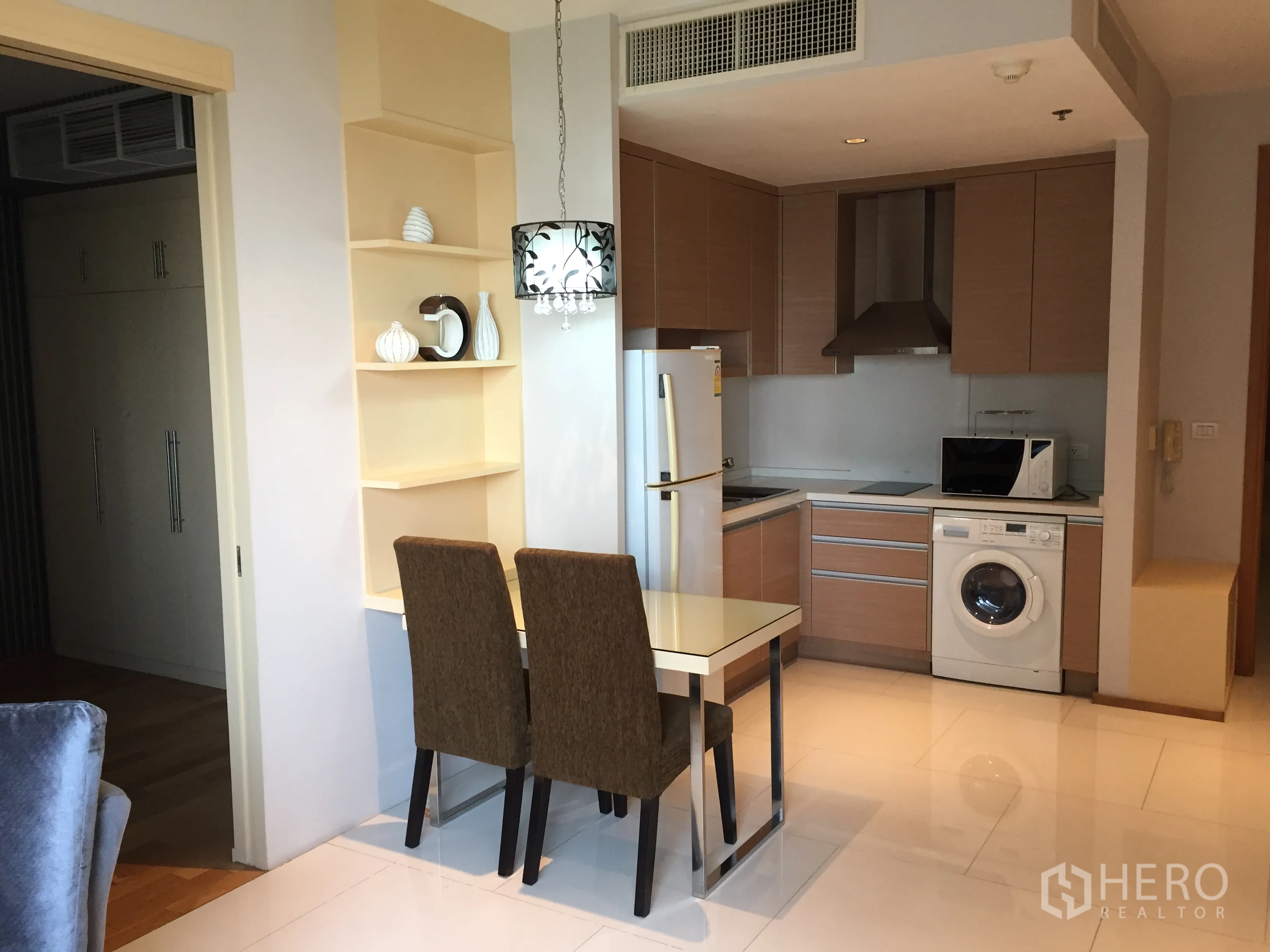 Condominium for rent or sale in Khlong Toei, Bangkok - Compact kitchen and dining nook with fridge, cooktop, microwave and in-unit washing machine in a 1-bedroom condo.