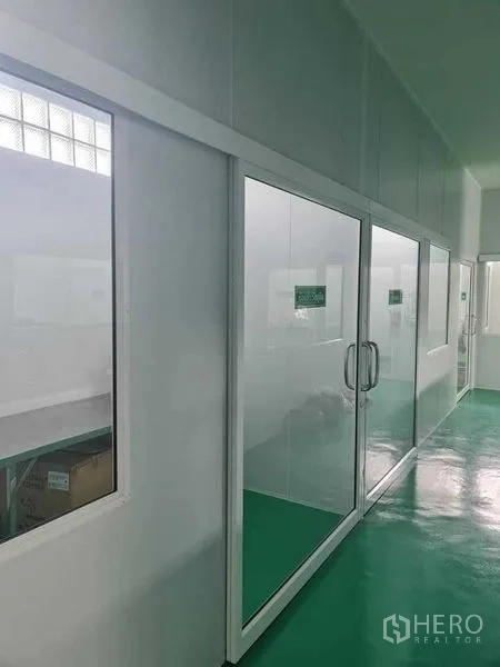 Factory for sale in Bang Pa-in, Phra Nakhon Si Ayutthaya - Corridor lined with glass-partitioned rooms inside a clean facility.