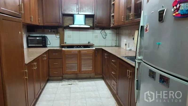 联排别墅 出租在Watthana, Bangkok - 封闭式厨房，木质橱柜、抽油烟机与冰箱。