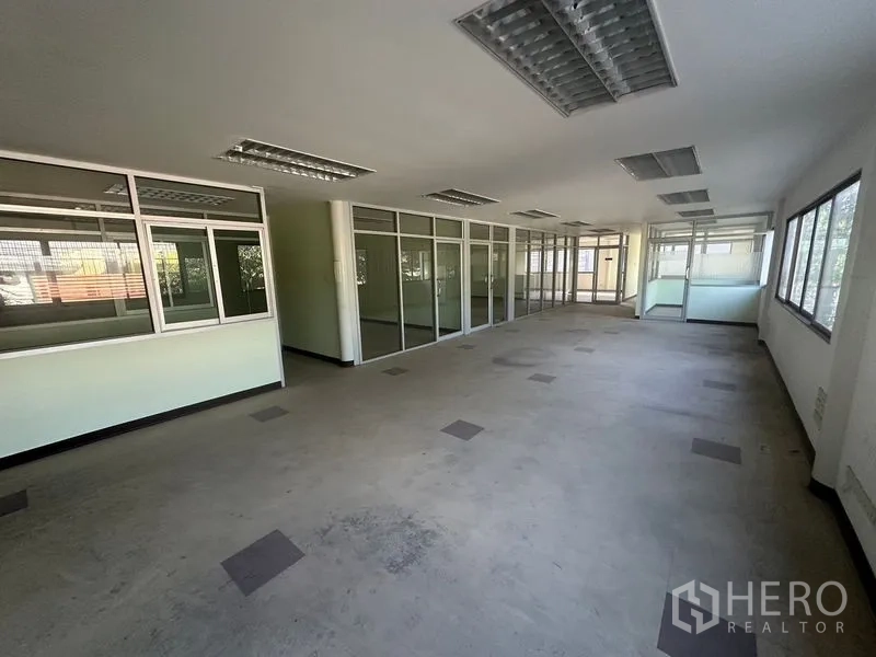 Warehouse for rent in Saphan Sung, Bangkok - Spacious office floor with glass partition walls and large windows in a warehouse complex.