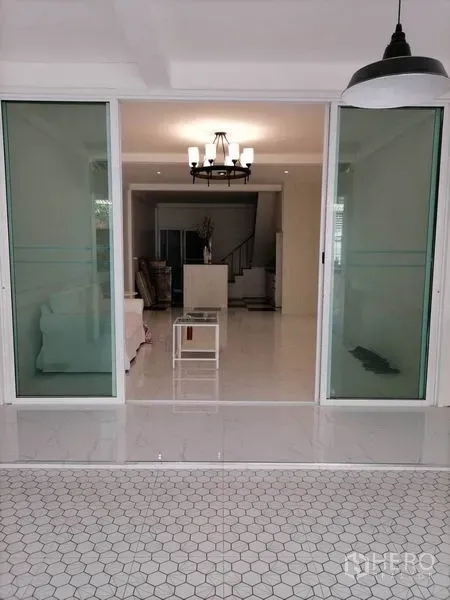 Townhouse for rent or sale in Khlong Toei, Bangkok - Sliding glass doors opening to a bright living room with chandelier lighting