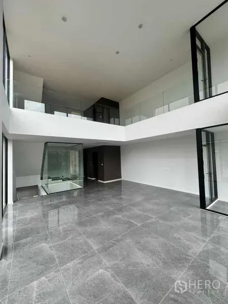 Home Office for rent or sale in Lat Phrao, Bangkok - Expansive double-height living or workspace with floor-to-ceiling glass and mezzanine gallery.