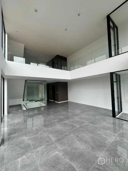 Home Office for rent or sale in Lat Phrao, Bangkok - Expansive double-height living or workspace with floor-to-ceiling glass and mezzanine gallery.