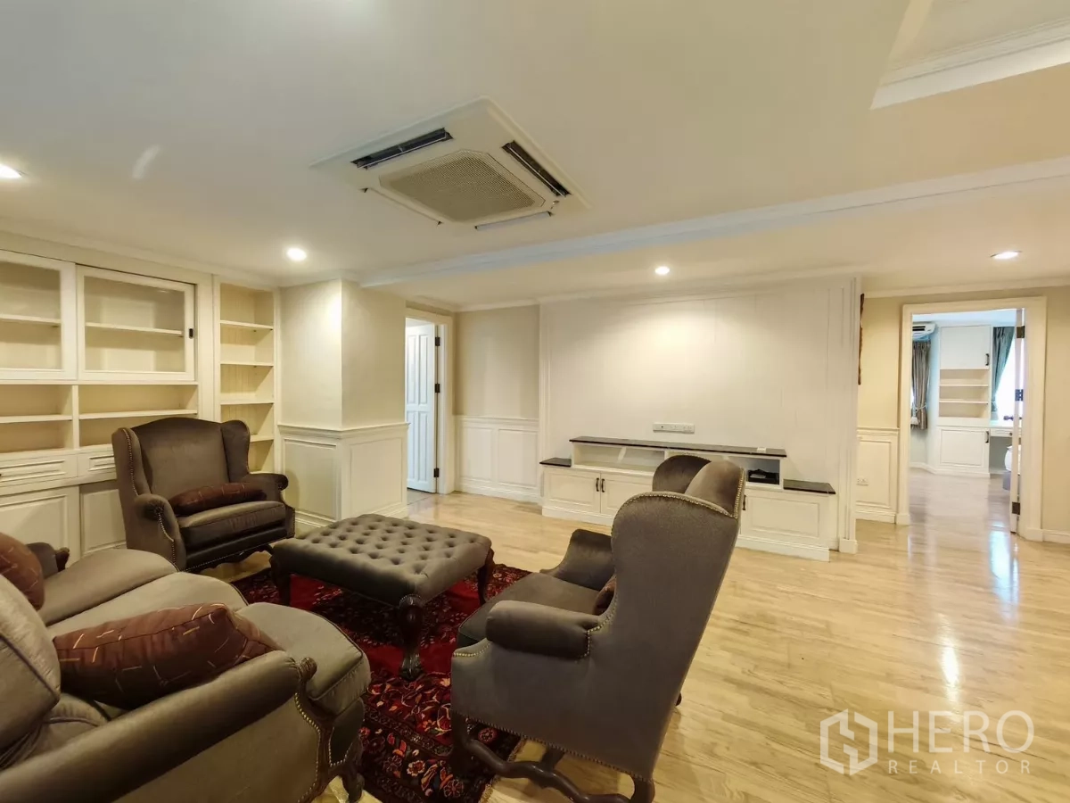 Condominium for rent in Pathum Wan, Bangkok - Living room with built-in bookcases, TV wall and doorway leading to bedrooms.