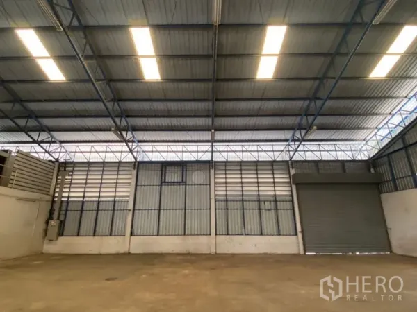 Factory for rent in Lat Lum Kaeo, Pathum Thani - Interior wall of the warehouse with strip lighting and a large roller shutter.