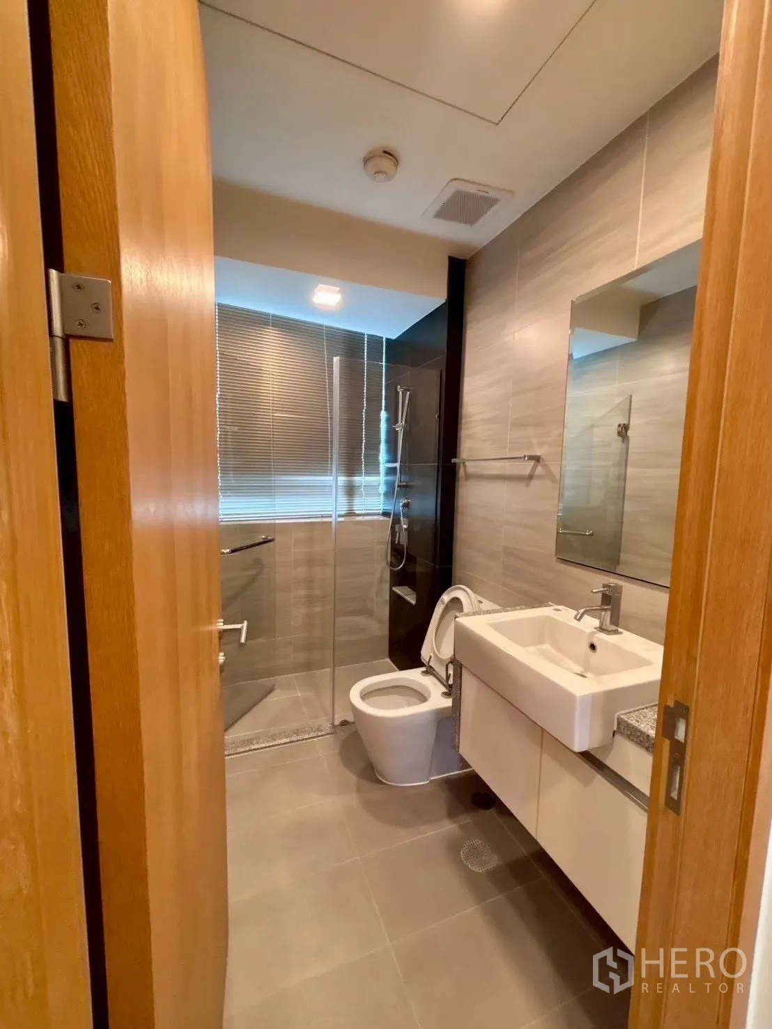 Condominium for rent in Khlong Toei, Bangkok - Contemporary bathroom with glass-enclosed shower, vanity and toilet
