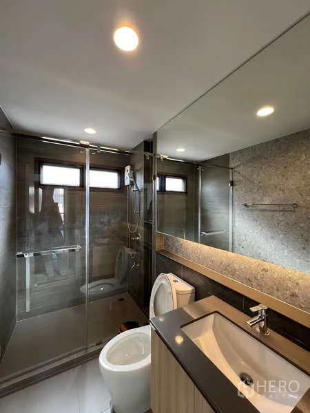 Detached House for rent in Bang Kapi, Bangkok - Sleek bathroom with glass shower, wall mirror and vanity sink.