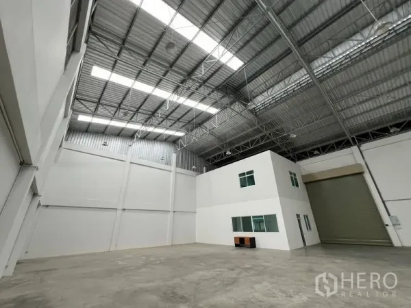 Factory for rent in Phra Samut Chedi, Samut Prakan - Spacious warehouse view showing white internal office block, steel roof and oversized roller door.