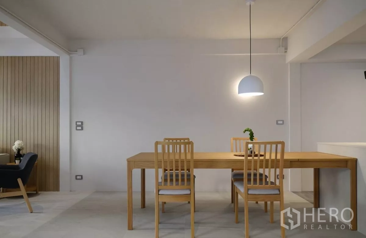 Townhouse for rent or sale in Watthana, Bangkok - Minimalist dining space with wooden table, four chairs and dome pendant lamp.