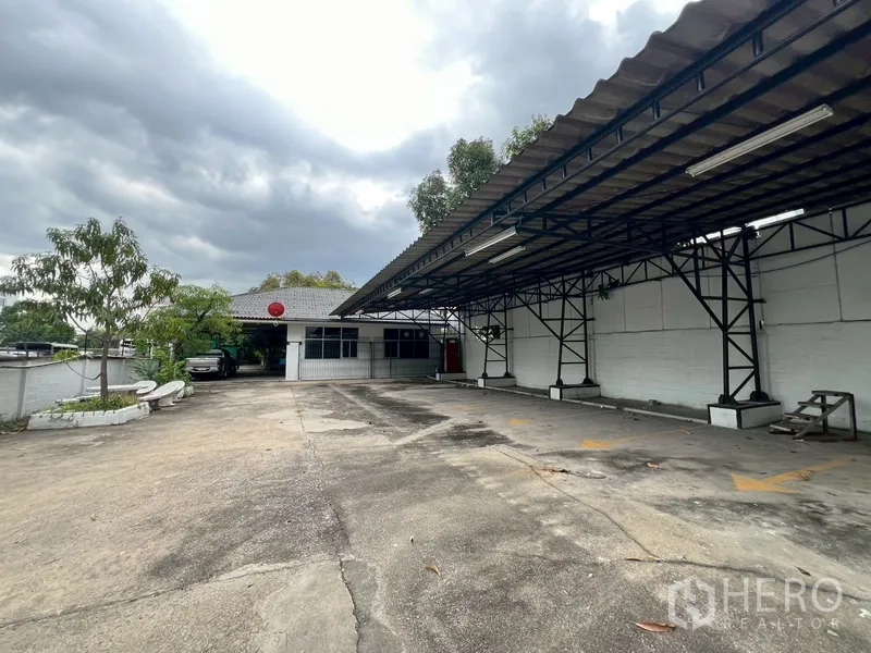 Shophouse for rent in Phra Khanong, Bangkok - Covered parking structure and driveway leading to an auxiliary building.