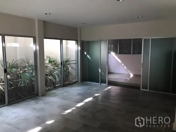 Townhouse for rent in Suan Luang, Bangkok - Spacious room with floor-to-ceiling sliding doors opening to an internal courtyard planter.