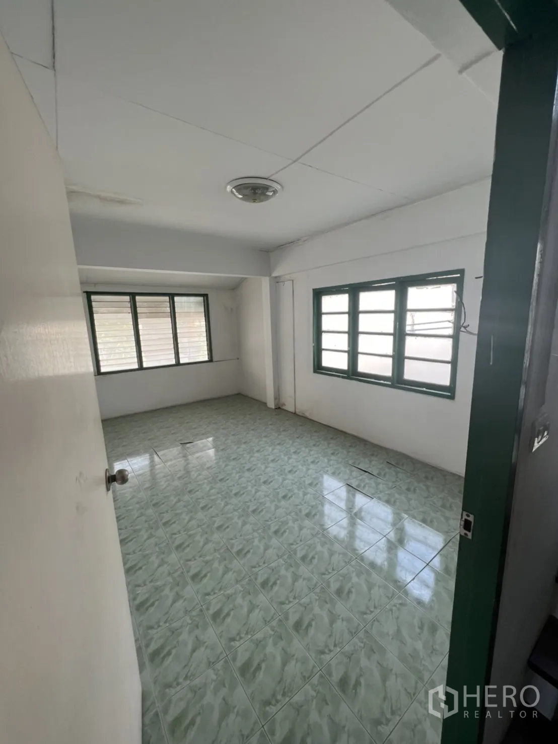 联排别墅 出售在Watthana, Bangkok - 楼上房间，绿色瓷砖地面与多扇窗户采光充足。