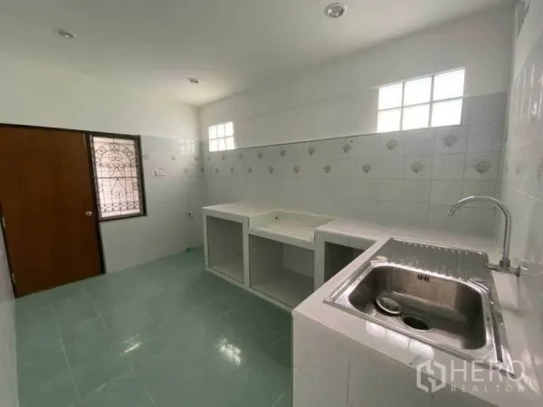 Detached House for rent in Huai Khwang, Bangkok - Bright tiled kitchen with built-in counter space and stainless sink.