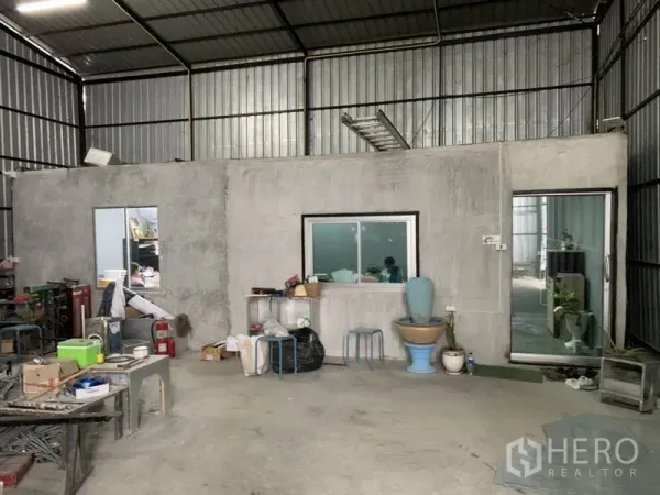 Warehouse for rent in Bang Kapi, Bangkok - Interior of warehouse featuring concrete office room with windows, sliding door and basic restroom.