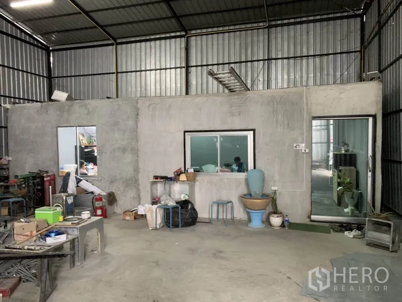 Warehouse for rent in Bang Kapi, Bangkok - Interior of warehouse featuring concrete office room with windows, sliding door and basic restroom.