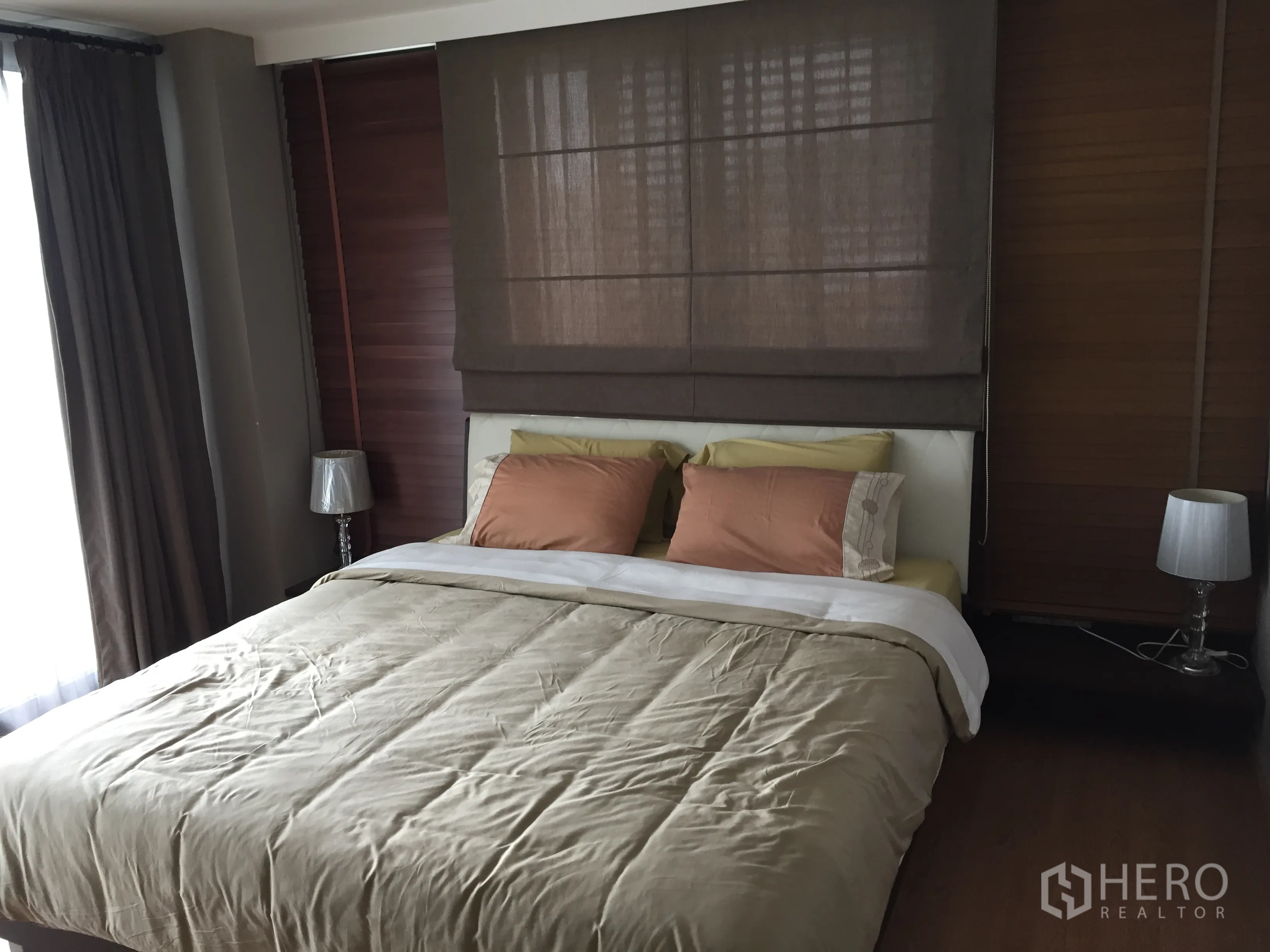 Condominium for rent in Watthana, Bangkok - Master bedroom with king bed, bedside lamps, blackout blinds, and large window bringing in natural light.