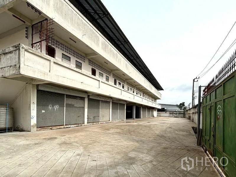 货栈 出租在Bang Khun Thian, Bangkok - 多扇卷闸装卸门，旁有安全的绿色滑动大门与车道。