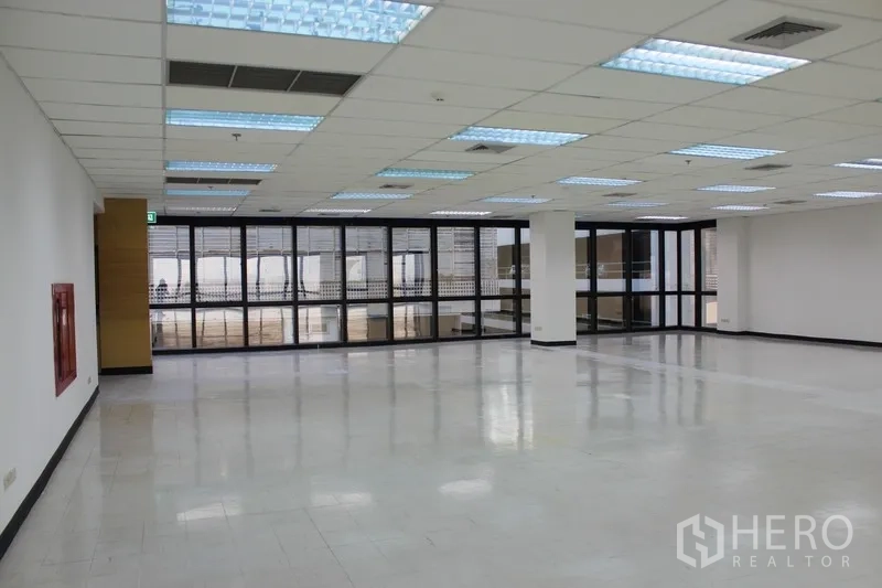 Office Space for rent in Watthana, Bangkok - Open workspace with fluorescent lighting, black-framed windows, and a wall-mounted fire safety cabinet.